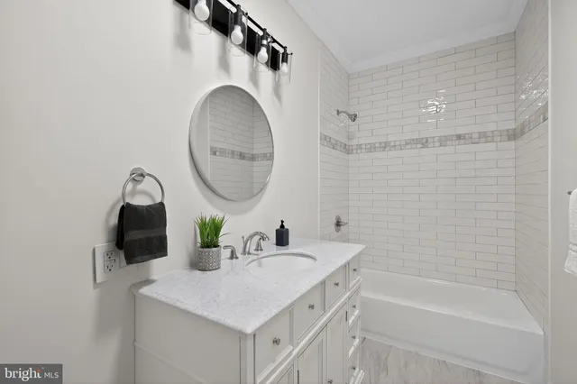a bathroom with a sink vanity mirror and tub