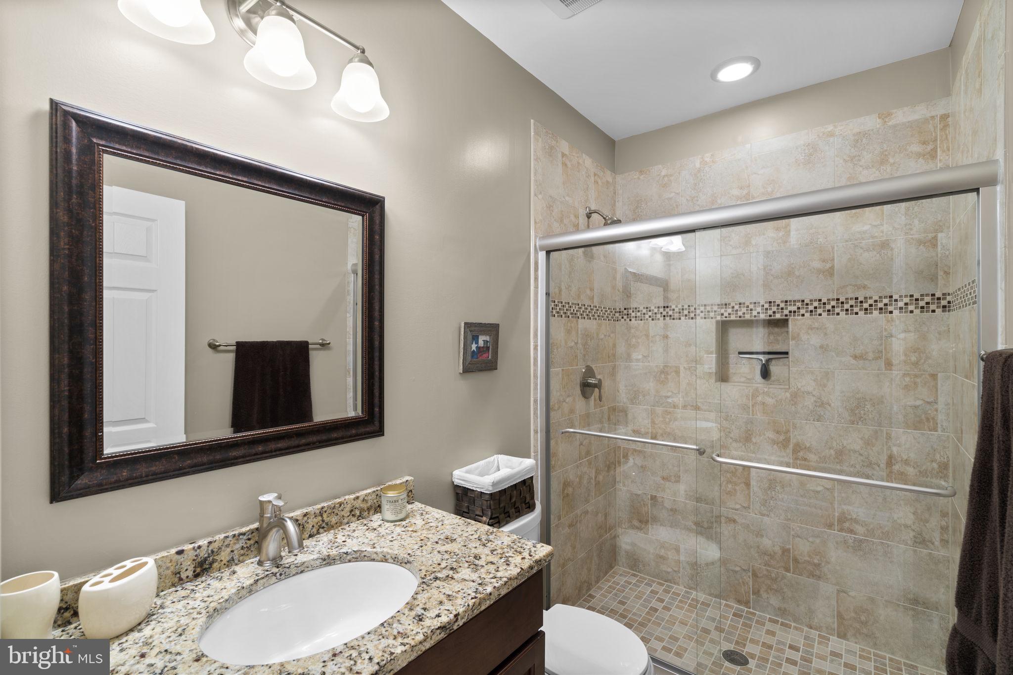 9323 Castle Hill Road Springfield, VA 22153 - Photo 74 of 95 a bathroom with a granite countertop sink toilet a mirror and shower