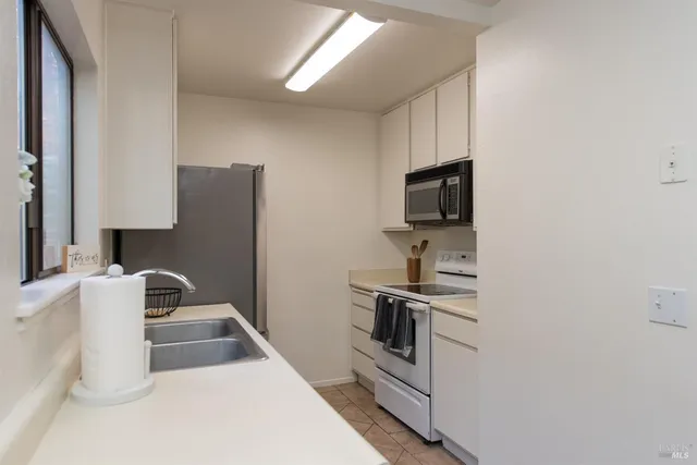 a kitchen with granite countertop a refrigerator stove and sink