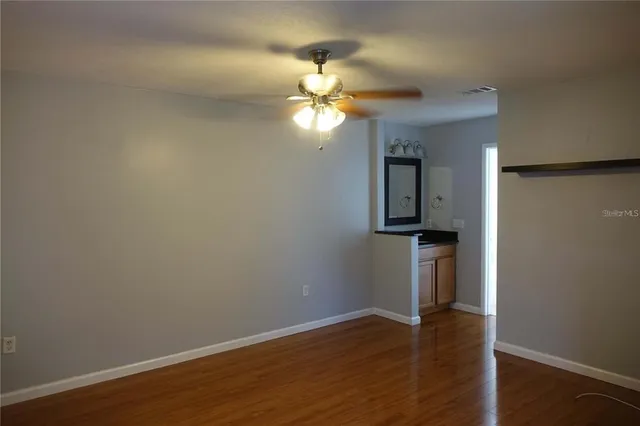 a view of a room with wooden floor and a ceiling fan