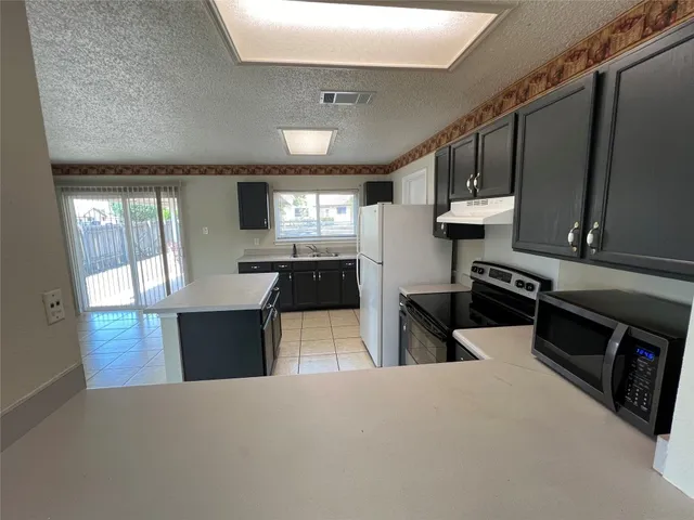 a large kitchen with a stove top oven a sink a counter space and cabinets