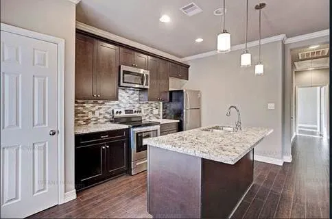 a kitchen with kitchen island granite countertop wooden cabinets and refrigerator