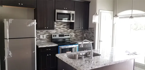 a kitchen with stainless steel appliances granite countertop a refrigerator and a sink