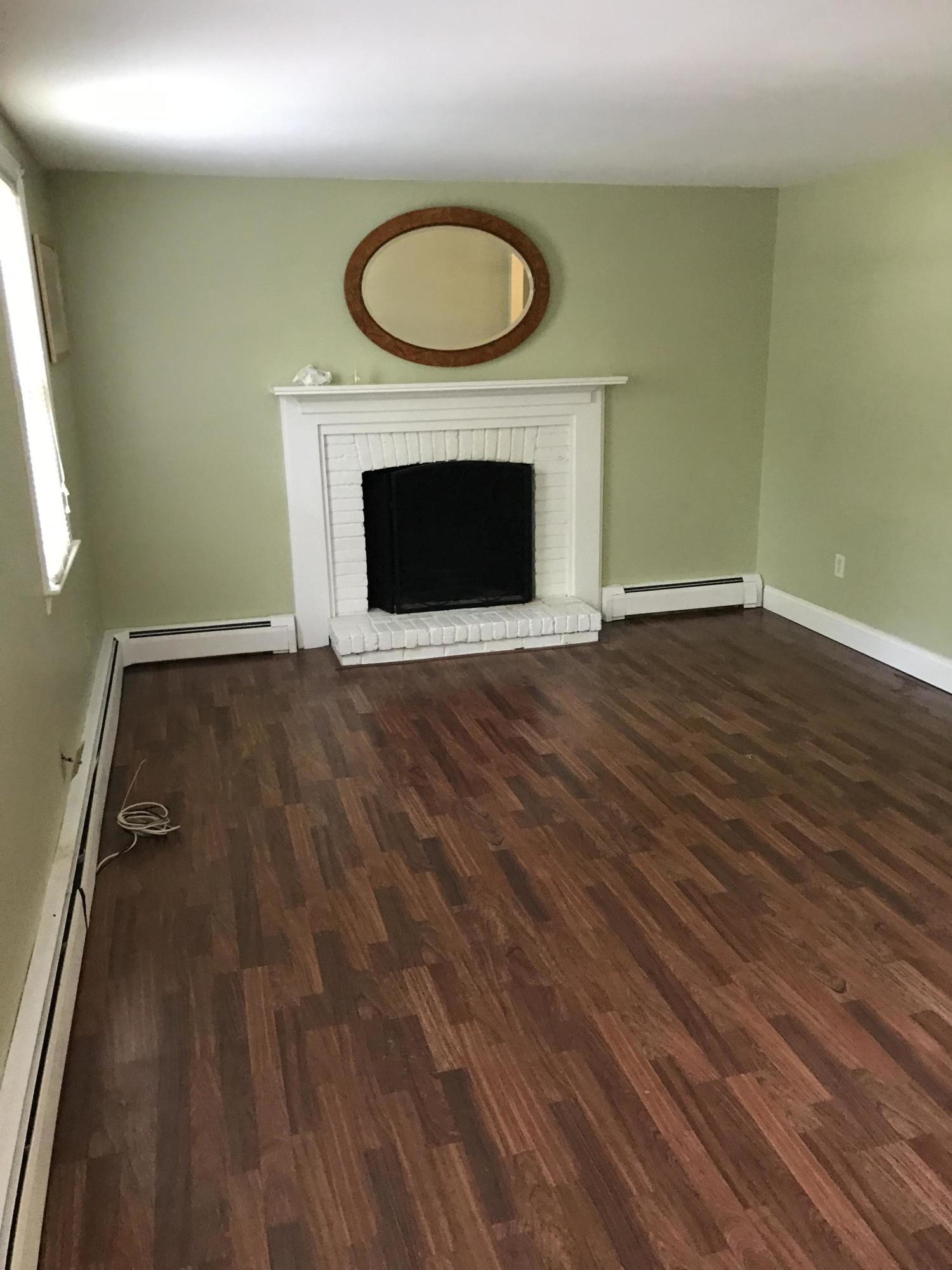 18 Stoney Cliff Road Centerville, MA 02632 - Photo 2 of 14 an empty room with wooden floor a fireplace and a window