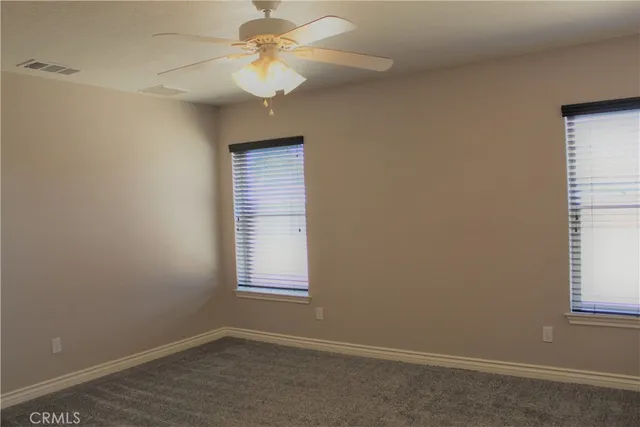 an empty room with windows and fan