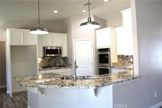 a room with kitchen island granite countertop a counter top space appliances and cabinets