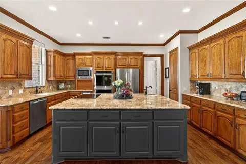 a kitchen with kitchen island granite countertop counter top space a sink stainless steel appliances and cabinets