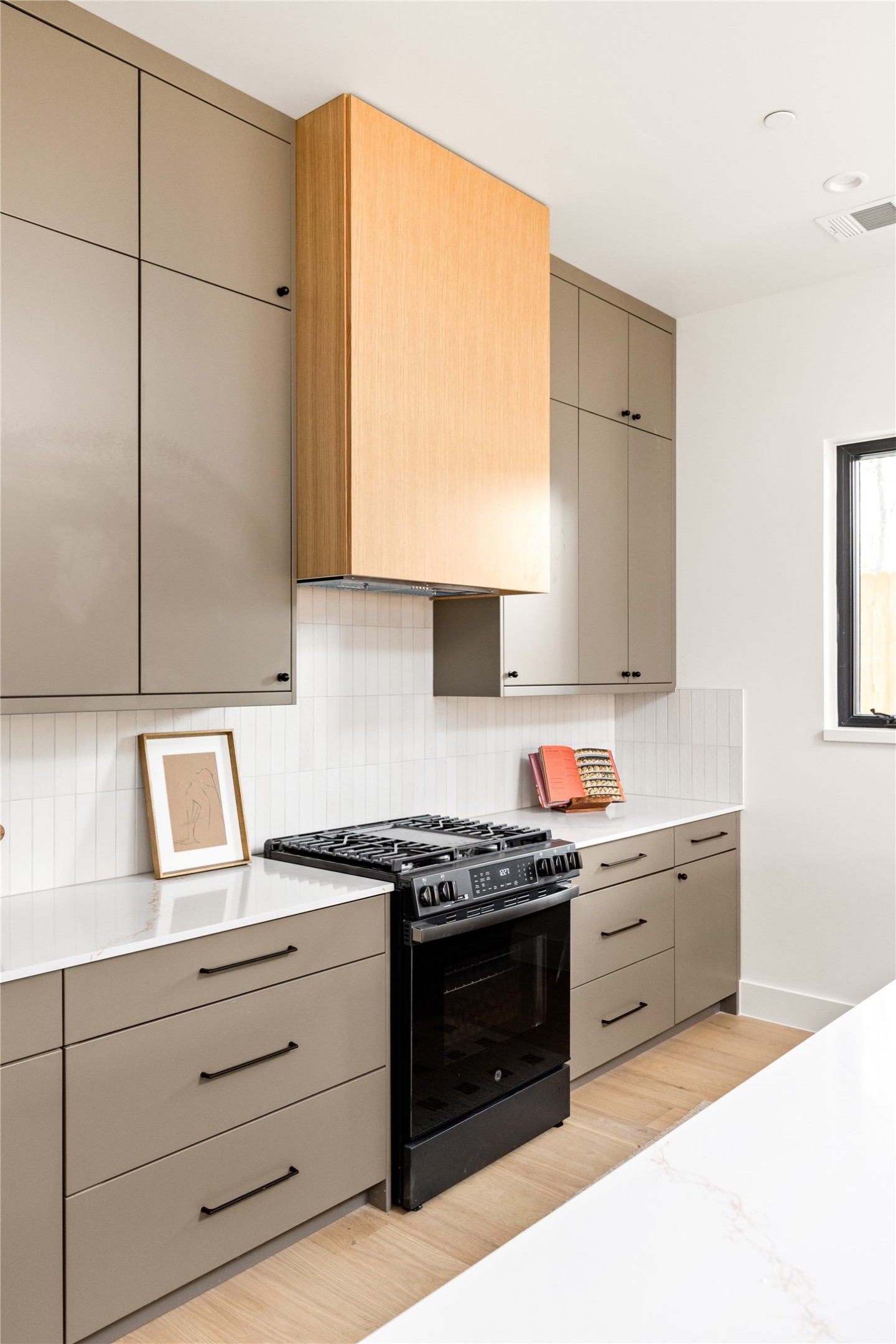 4414 South 1st Street, Unit 3 Austin, TX 78745 - Photo 18 of 39 Kitchen with gray cabinets, gas stove, light wood-type flooring, and tasteful backsplash