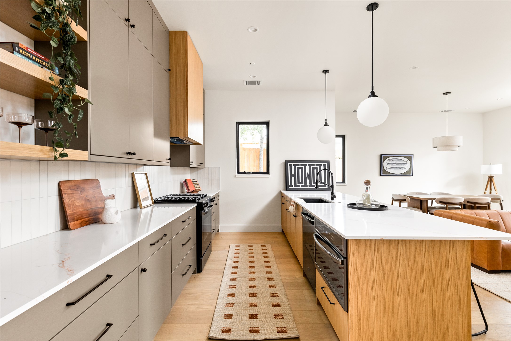 4414 South 1st Street, Unit 3 Austin, TX 78745 - Photo 19 of 39 Two tone kitchen with open shelves, a kitchen breakfast bar, dual tone cabinets, decorative light fixtures, and black range with gas cooktop