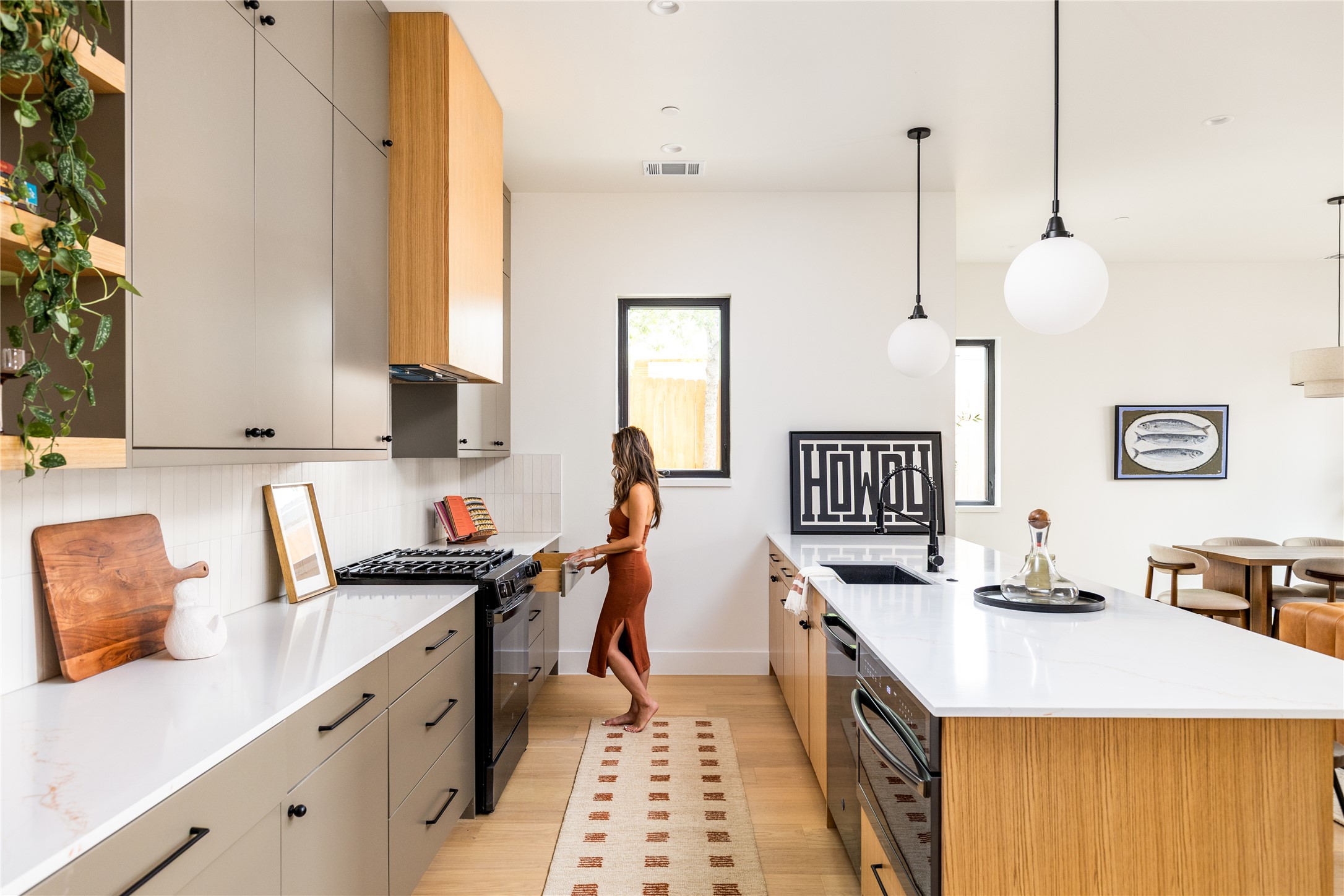 4414 South 1st Street, Unit 3 Austin, TX 78745 - Photo 9 of 39 Kitchen with two tone color scheme, black appliances, hanging light fixtures, decorative backsplash, and light wood-type flooring