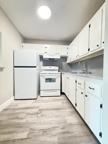 a kitchen with cabinets appliances a sink and a refrigerator