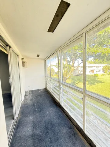 a view of an empty room with wooden floor and door