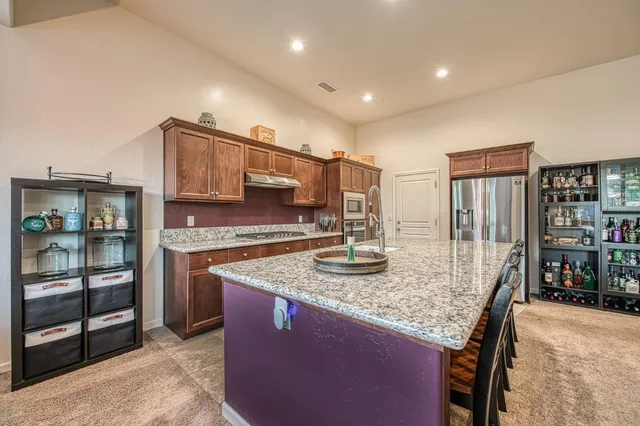 a kitchen with granite countertop kitchen island stainless steel appliances a sink stove and cabinets