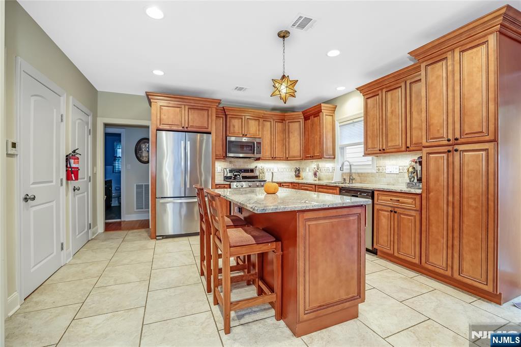 165 Pine Street Hackensack, NJ 07601 - Photo 10 of 41 a kitchen with stainless steel appliances granite countertop a refrigerator a sink dishwasher and a stove with wooden cabinets