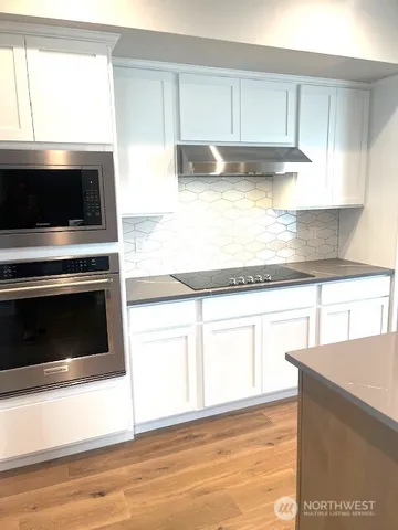 a kitchen with granite countertop a stove and a white cabinets