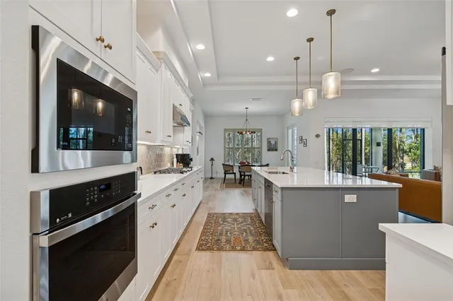 a living room with furniture kitchen view and a chandelier