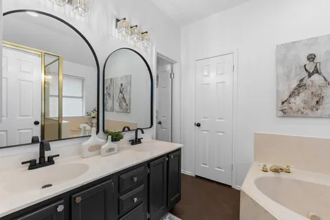 a bathroom with a double vanity sink mirror and bathtub