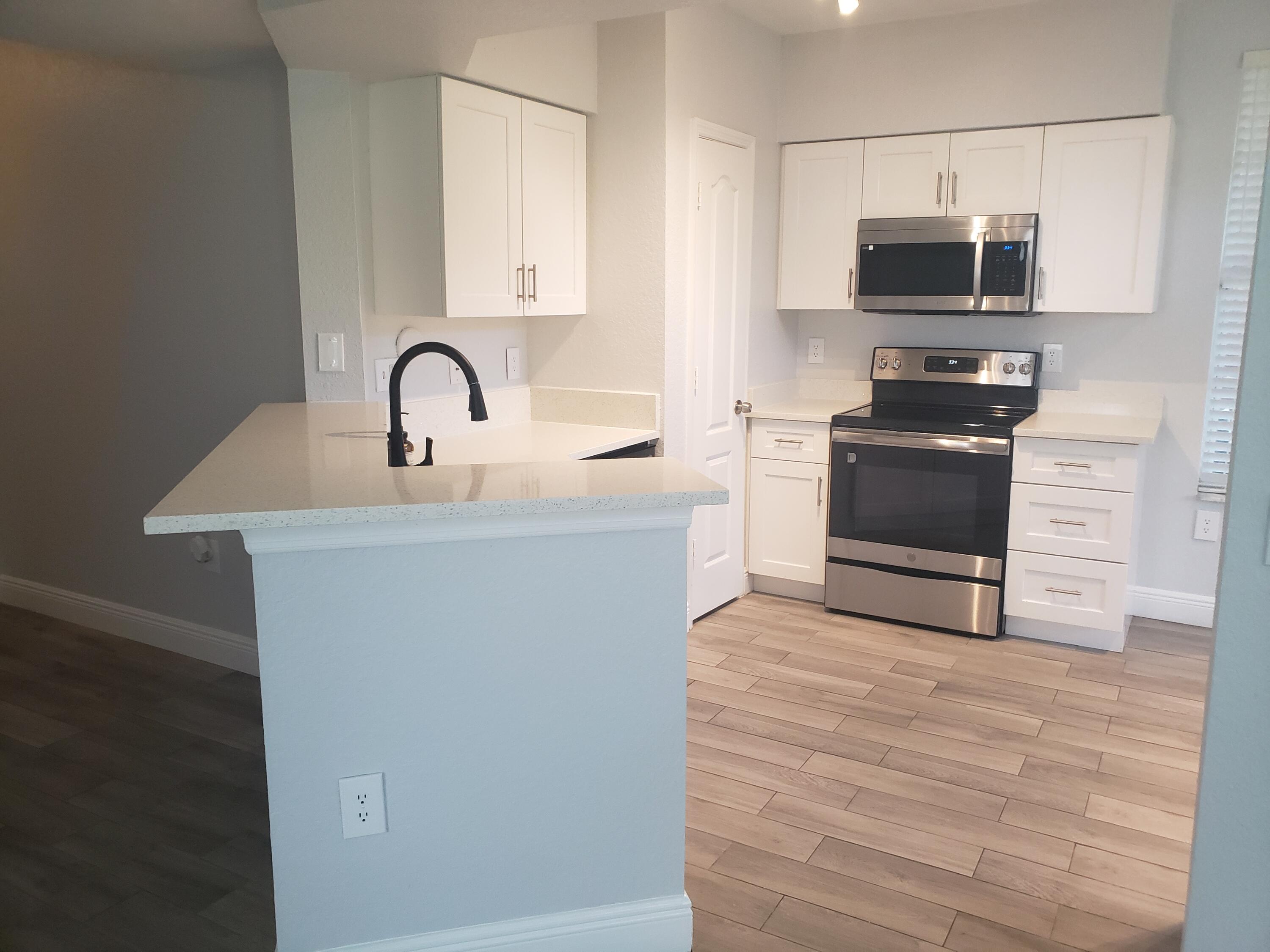 909 Belmont Place, Unit 909 Boynton Beach, FL 33436 - Photo 1 of 26 a kitchen with stainless steel appliances granite countertop a stove top oven a sink and dishwasher