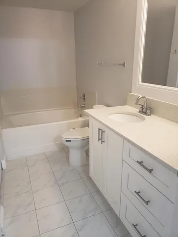 a spacious bathroom with a granite countertop toilet a sink and bathtub
