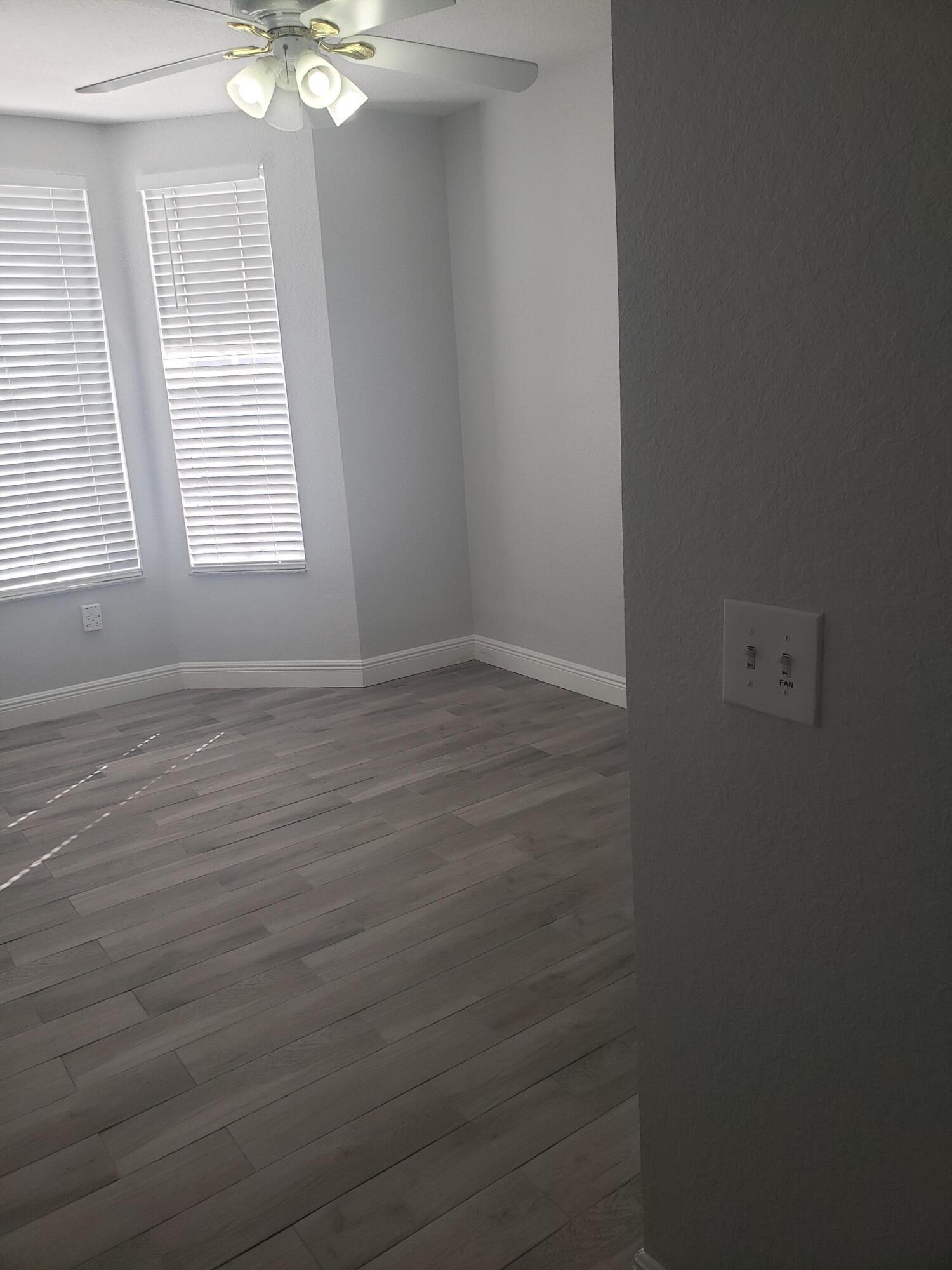 909 Belmont Place, Unit 909 Boynton Beach, FL 33436 - Photo 18 of 26 an empty room with wooden floor fan and windows