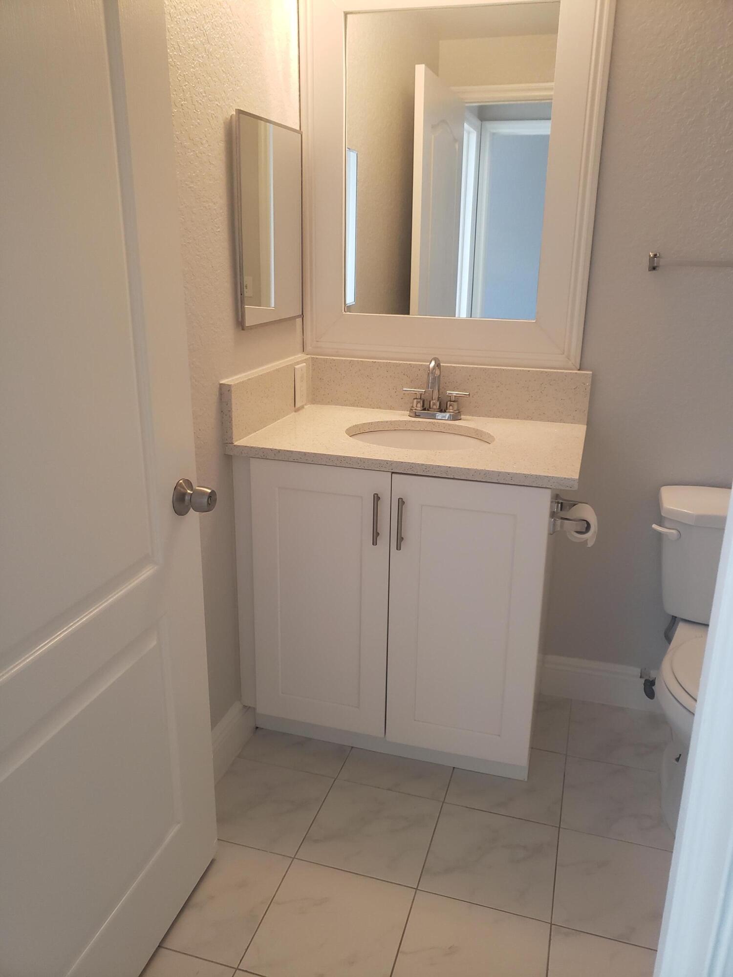 909 Belmont Place, Unit 909 Boynton Beach, FL 33436 - Photo 20 of 26 a bathroom with a sink a toilet and a mirror
