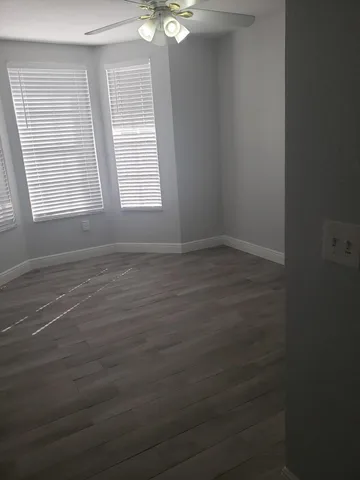 an empty room with windows and fan