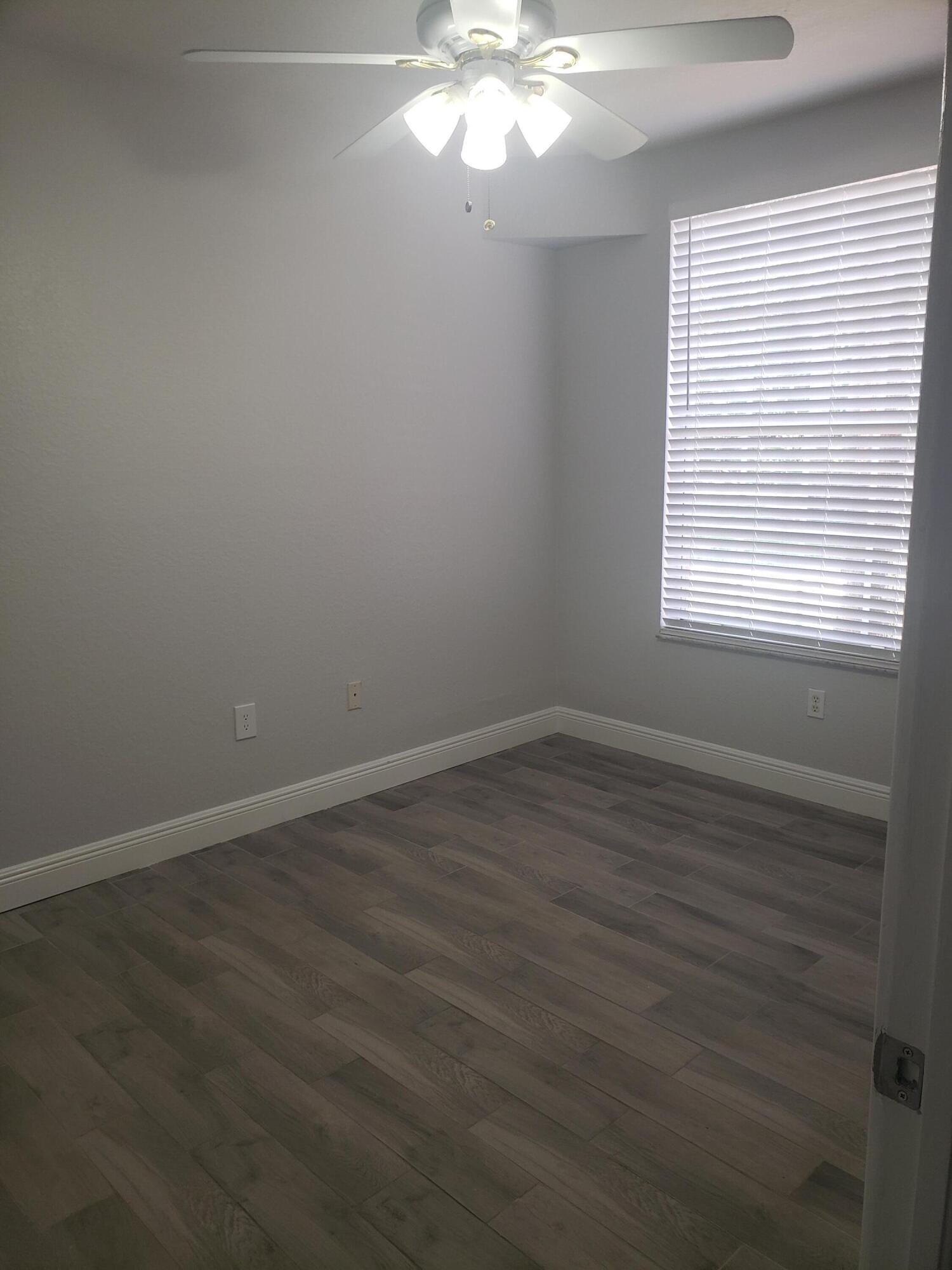 909 Belmont Place, Unit 909 Boynton Beach, FL 33436 - Photo 24 of 26 an empty room with wooden floor and windows