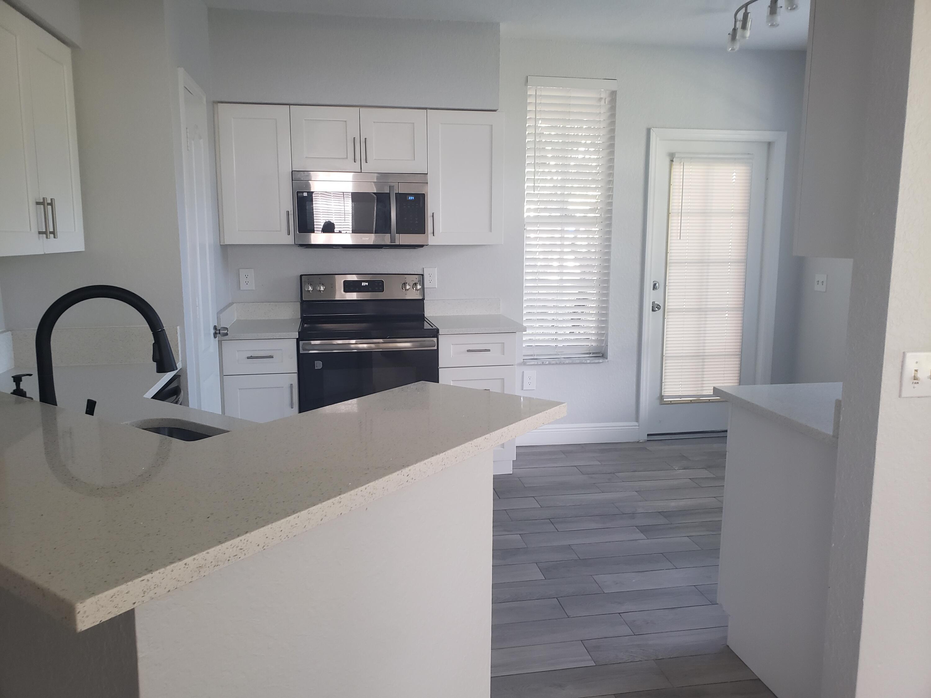 909 Belmont Place, Unit 909 Boynton Beach, FL 33436 - Photo 6 of 26 a kitchen with granite countertop a stove and a microwave