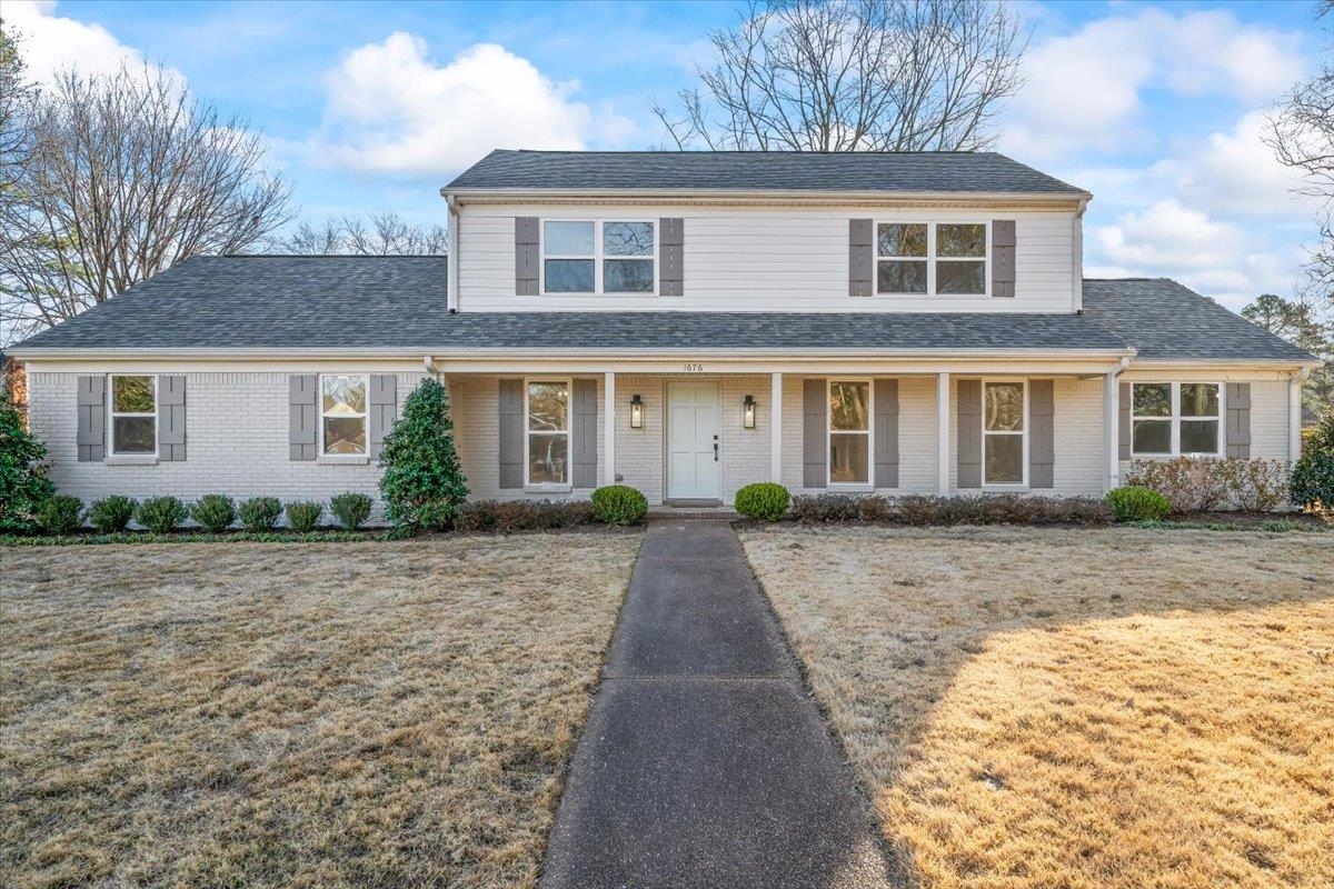 1676 Miller Farms Road Germantown, TN 38138 - Photo 1 of 37 Two-story residence featuring a white brick and siding exterior, dark gray shingle roof, and a covered porch with white columns