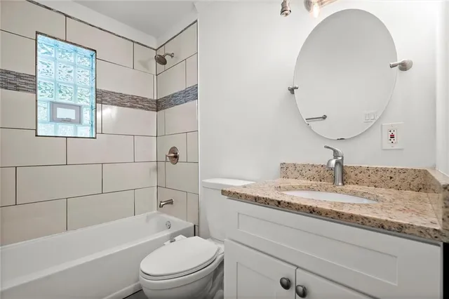 a bathroom with a granite countertop sink toilet mirror and bathtub