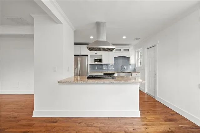 a large kitchen with stainless steel appliances granite countertop a sink a stove and a wooden floors