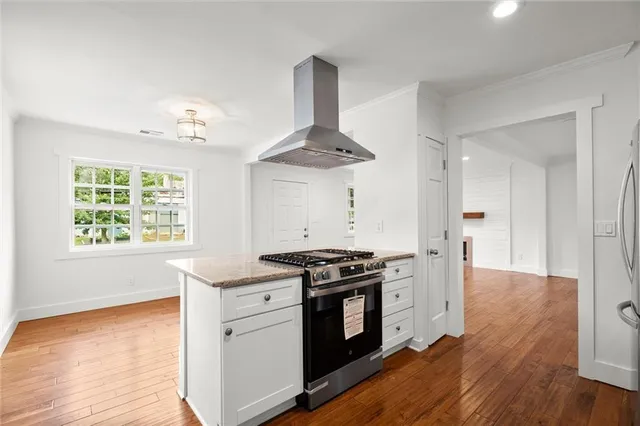 a kitchen with stainless steel appliances a stove and white cabinets with wooden floor