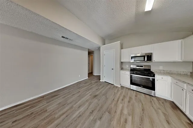 a kitchen with granite countertop a refrigerator and a stove top oven