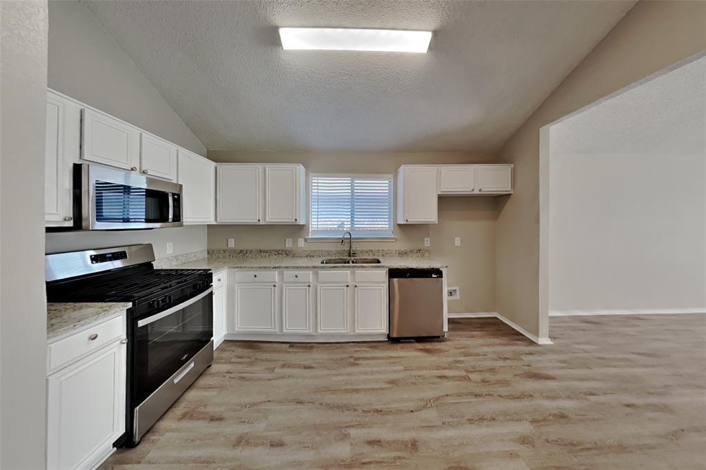 1924 Overland Street Fort Worth, TX 76131 - Photo 7 of 27 a kitchen with granite countertop white cabinets and stainless steel appliances