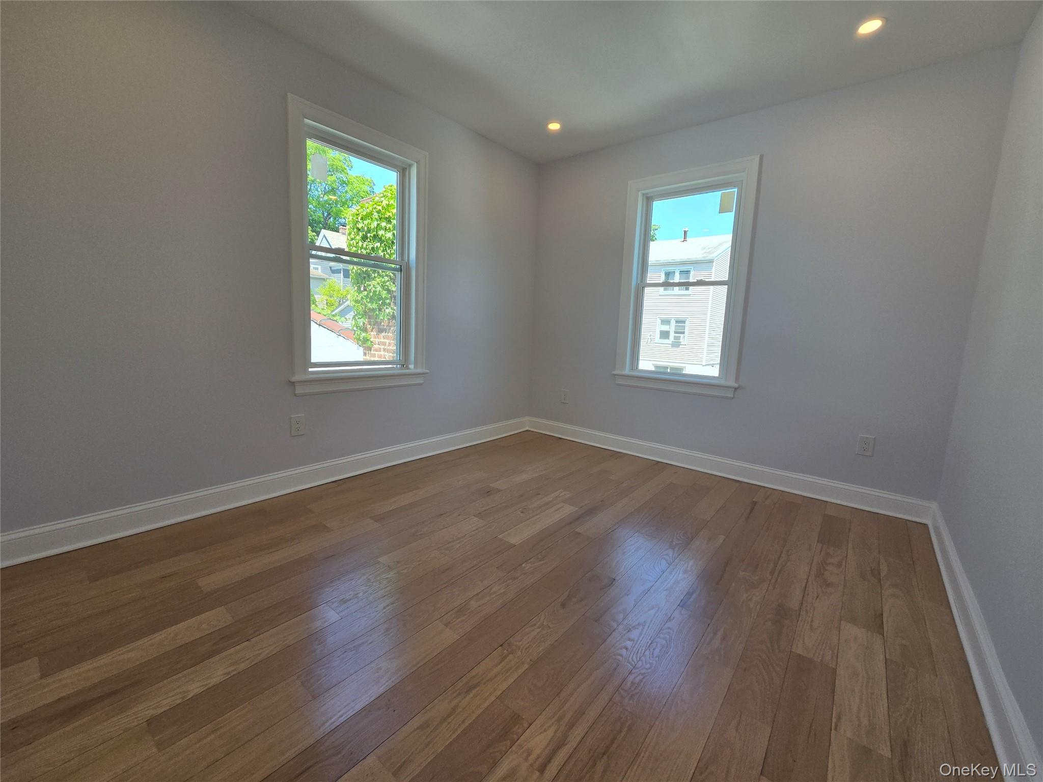 965 Main Street, Unit 2 New Rochelle, NY 10801 - Photo 10 of 12 Room with wood-finish flooring, two windows with white trim, recessed lighting, and light-toned walls