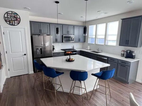 a kitchen with stainless steel appliances a dining table chairs refrigerator and sink