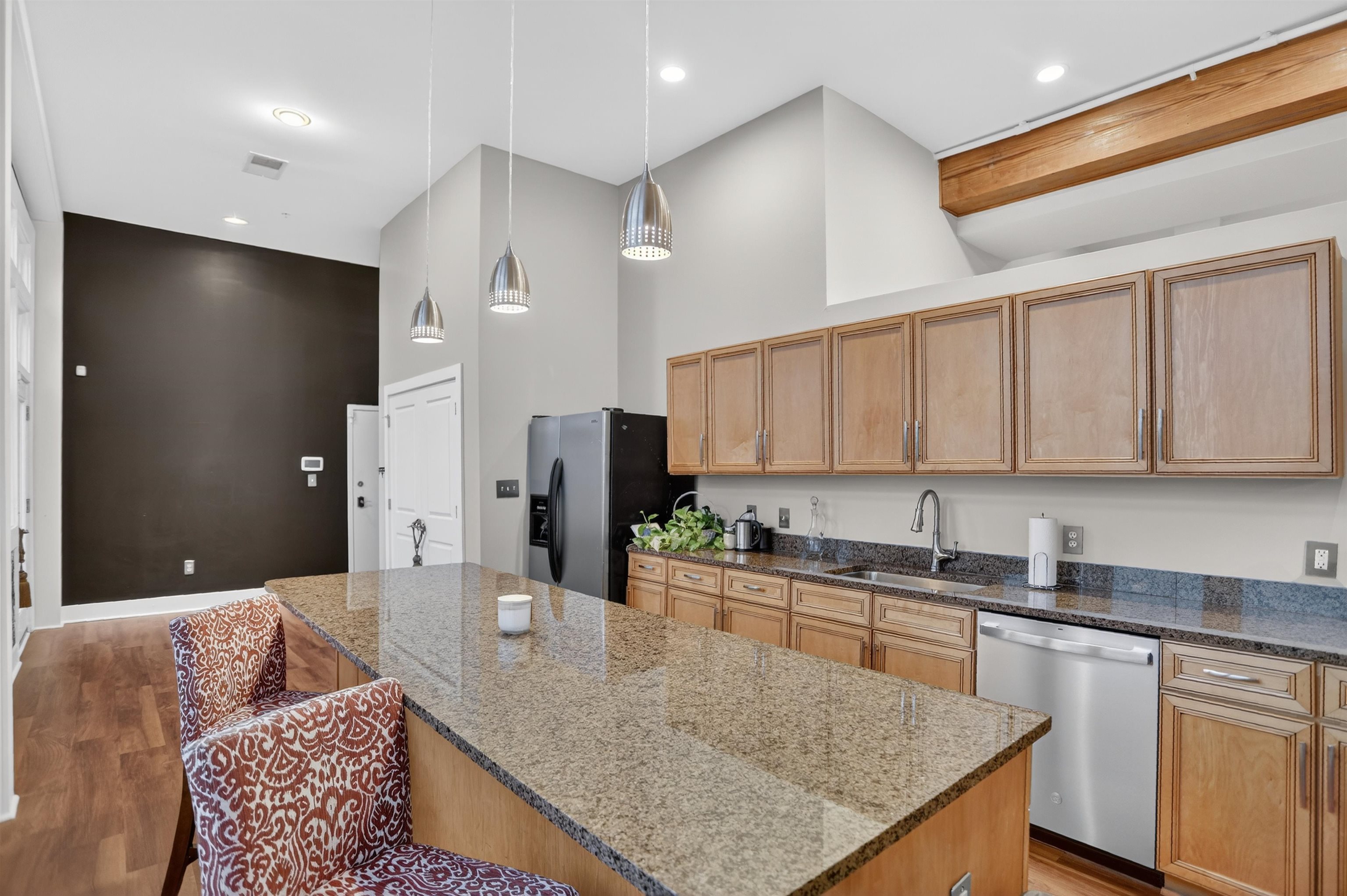 435 South Front Street, Unit 307 Memphis, TN 38103 - Photo 7 of 40 Kitchen featuring hanging light fixtures, stainless steel appliances, a kitchen breakfast bar, dark stone counters, and a towering ceiling