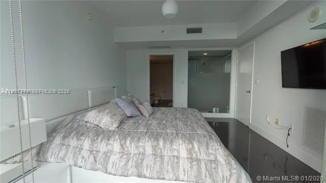 a bedroom with a bed and a flat tv screen on dresser