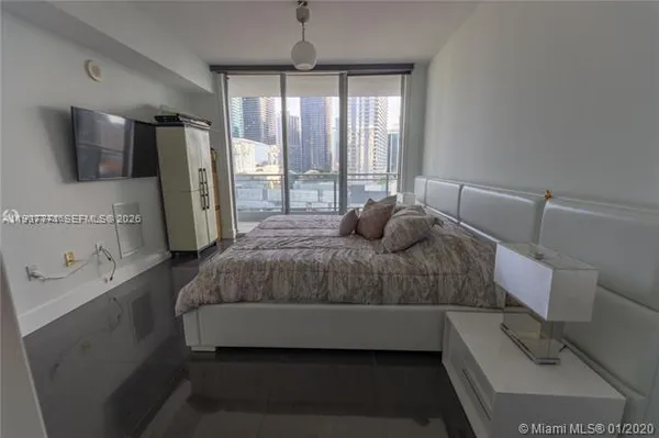 a bedroom with a bed and a flat tv screen on the dresser