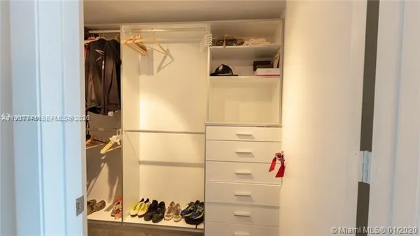 a view of walk in closet with clothes and shoes