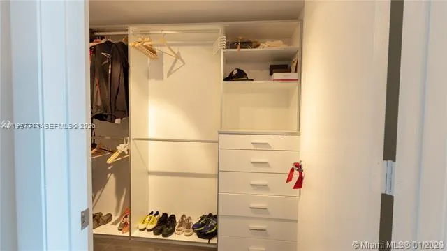 a view of walk in closet with clothes and shoes