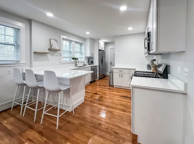 a large kitchen with kitchen island a dining table chairs and white cabinets