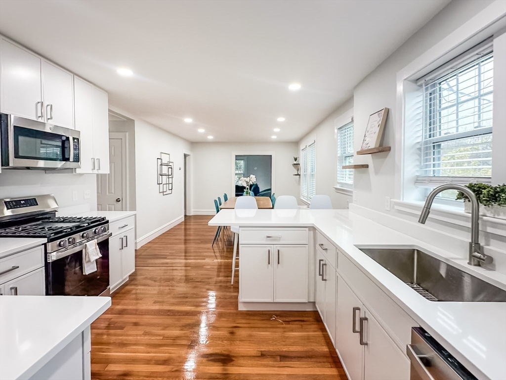 65-67 St James Circle, Unit 2 Newton, MA 02458 - Photo 13 of 29 a large kitchen with stainless steel appliances granite countertop a sink and dishwasher a stove top oven with wooden floor