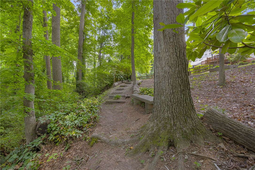 218 Northridge Drive Anderson, SC 29621 - Photo 46 of 50 A tranquil pathway meanders through verdant woods, leading to a serene seating area amidst nature.