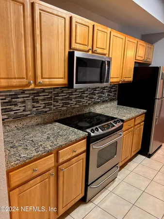 a kitchen with granite countertop a stove top oven microwave and cabinets