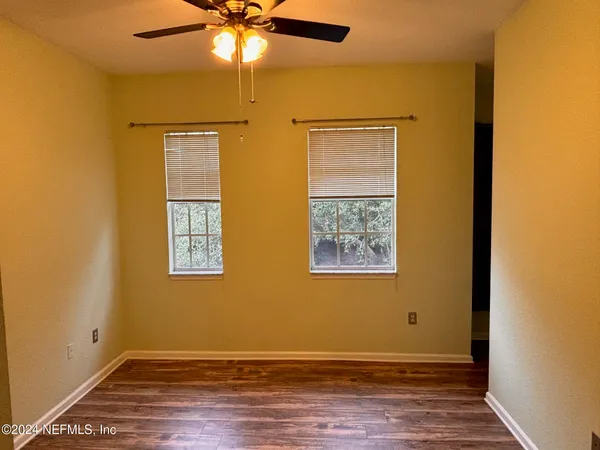 a view of empty room with wooden floor and fan