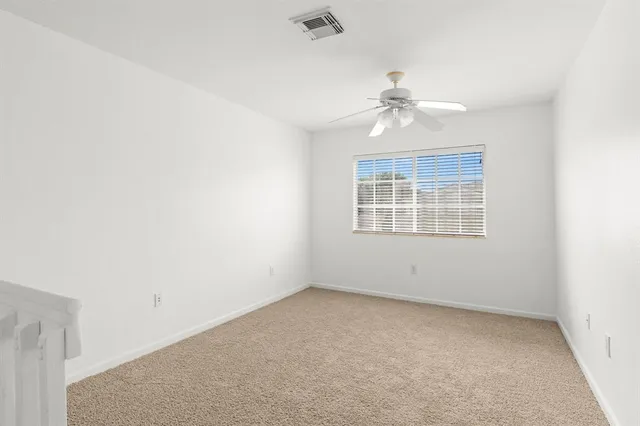 an empty room with chandelier fan and windows