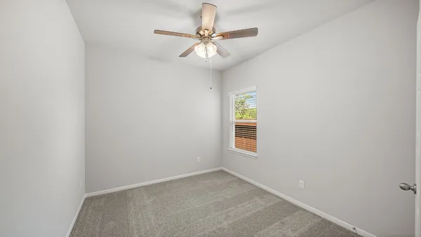 an empty room with a window and a fan