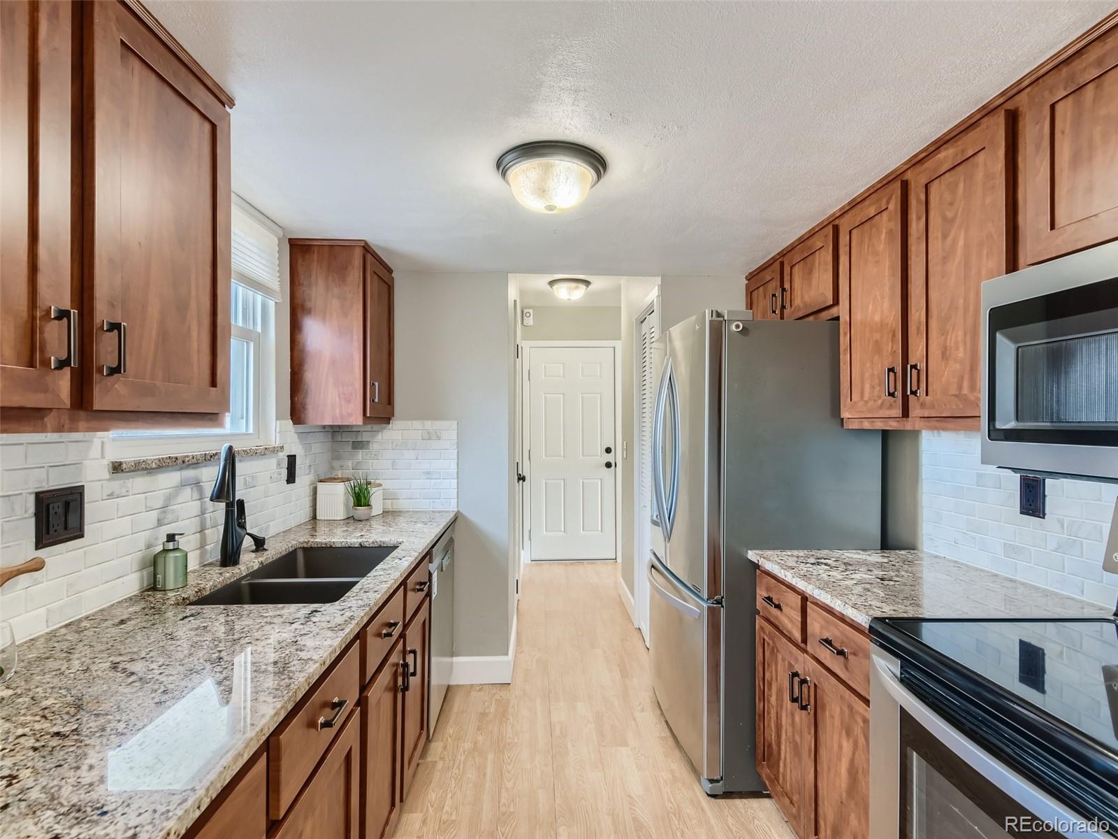 10390 Owens Circle Westminster, CO 80021 - Photo 10 of 28 a kitchen with stainless steel appliances granite countertop a sink stove and refrigerator