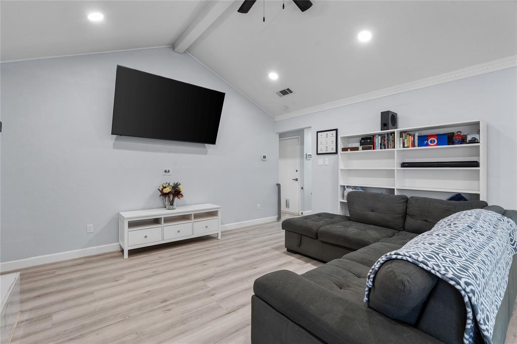 Vaulted ceiling with exposed beam, recessed lighting, wood-finish flooring, and built-in shelving